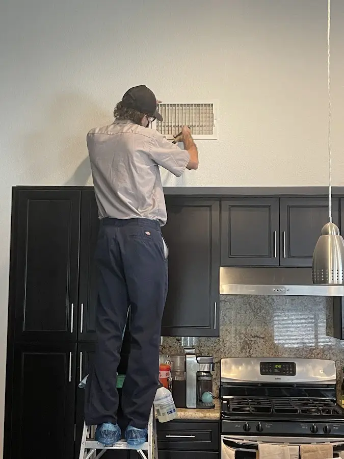 Technician inspecting an air vent during HVAC service in Emmett